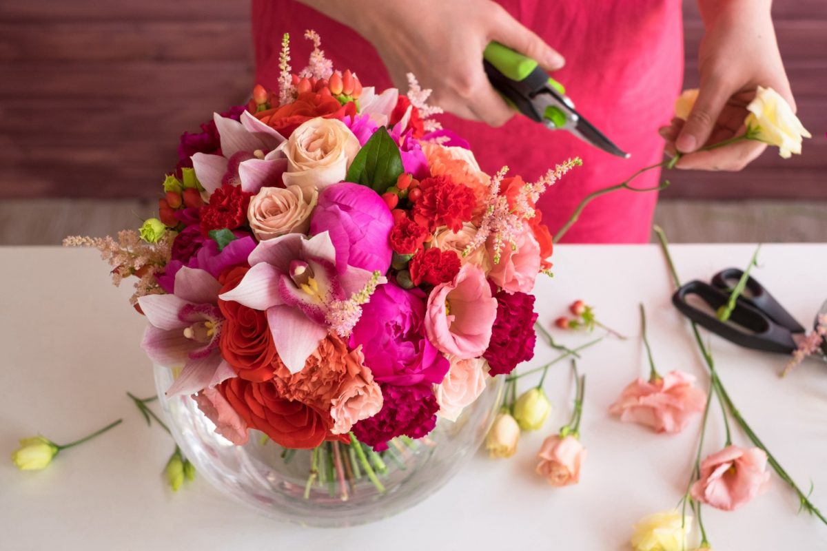 Women creating a flower arrangement with pink and red flowers
